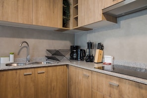 A modern kitchen with wooden cabinets, a stainless steel sink, and a coffee maker. - Porvenir Apartments by Andes. Parking. (Santiago)