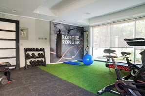 A gym with exercise equipment, a punching bag, and a wall with motivational text. - Porvenir Apartments by Andes. Parking. (Santiago)
