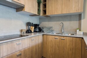 Een keuken met houten kastjes, een roestvrijstalen spoelbak, een koffiezetapparaat en een messenblok.