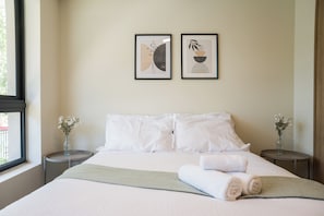 A hotel room with a bed, two bedside tables, a window, and two framed artworks on the wall. - Porvenir Apartments by Andes. Parking. (Santiago)