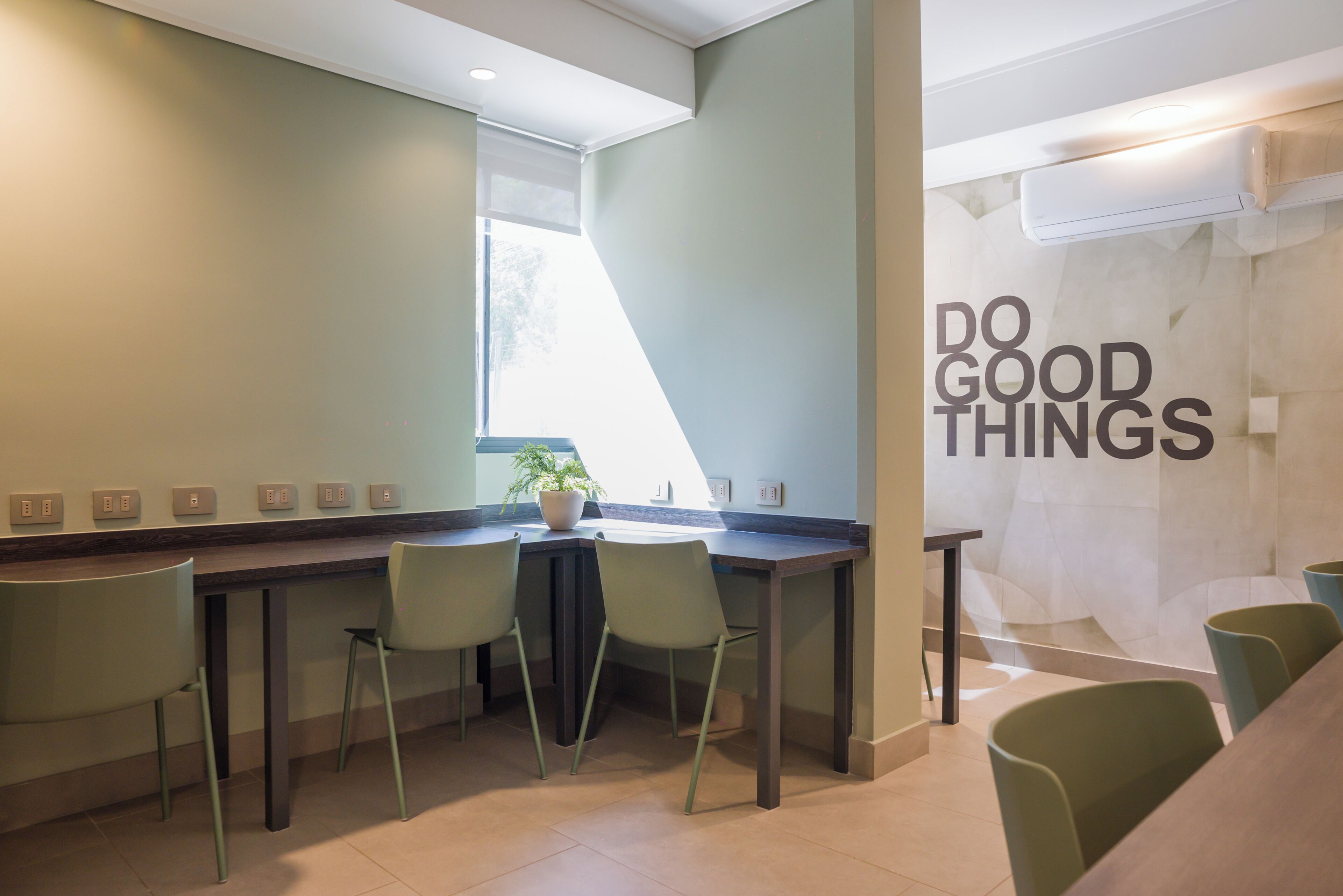 A modern kitchen with a dining area, a potted plant, and a motivational wall.