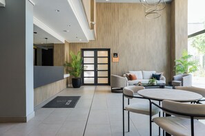 Een moderne lobby met een receptiebalie, een zithoek en een groot raam.