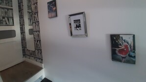 Ein Flur mit Bücherregal, drei gerahmten Bildern an der Wand und einer Tür.