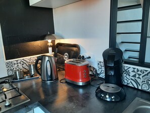 A kitchen with a gas stove, a kettle, a toaster, a coffee maker, and a toaster oven. - Duplex for 2 people in the St. Charles neighborhood, with a terrace overlooking the ocean and the golf course within walking distance (Biarritz)