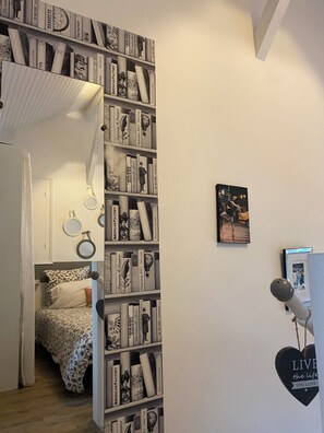 A room with a bookshelf, a bed with patterned bedding, and a wall with framed pictures and a heart-shaped decoration. - Duplex for 2 people in the St. Charles neighborhood, with a terrace overlooking the ocean and the golf course within walking distance (Biarritz)