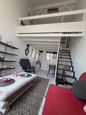 Ein Loft-Zimmer mit Bett, Essbereich und Treppe.