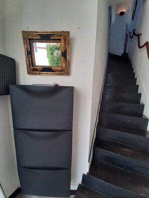 Een trap met een donkere leuning en treden, een aan de muur bevestigd fotolijstje, en een zwart object aan de wand.