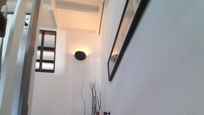 Eine Treppe mit roter Handlauf, einer Wandleuchte und einem gerahmten Bild.