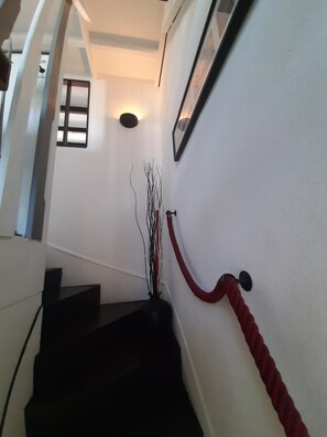 Eine Treppe mit roter Handlauf, einer Wandleuchte und einem gerahmten Bild.