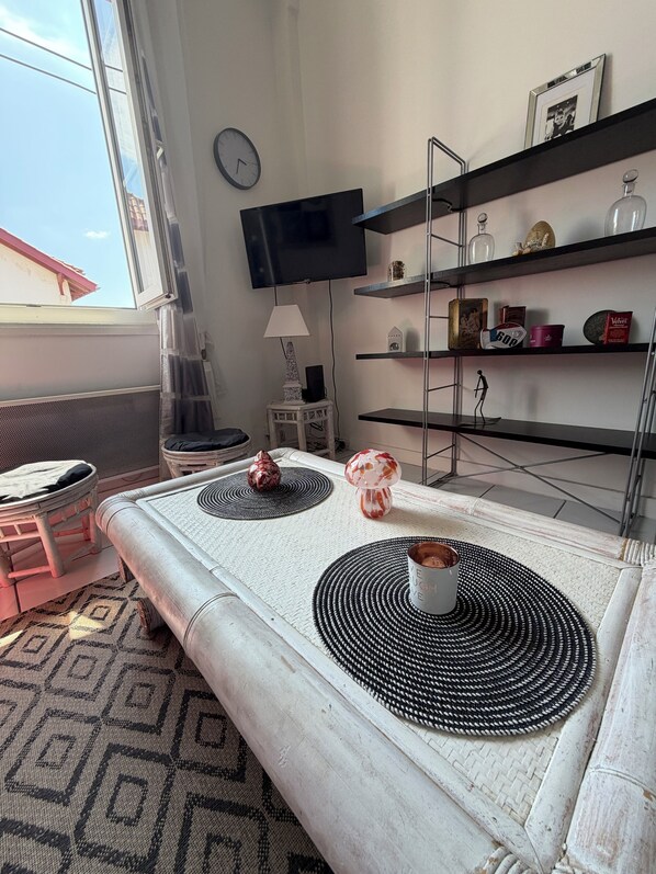 Een woonkamer met een bank, een televisie, een lamp en planken met decoratieve spullen.
