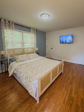 A bedroom with a bed, a television on the wall, and a window with curtains. - Starling House/Huge Fenced Yard/Pet-Friendly (Mableton)