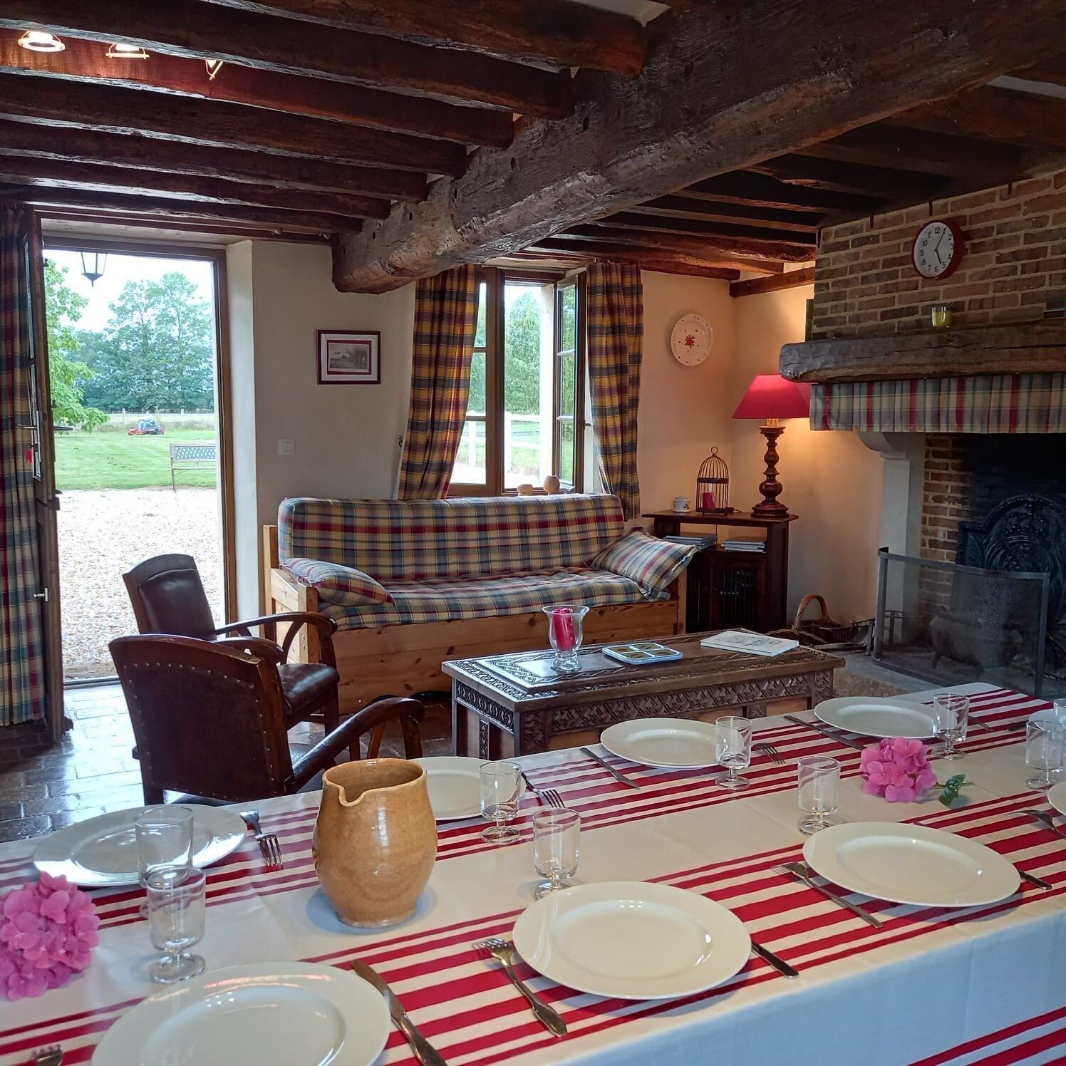 Un coin repas avec une table dressée pour quatre personnes, un canapé et une cheminée.