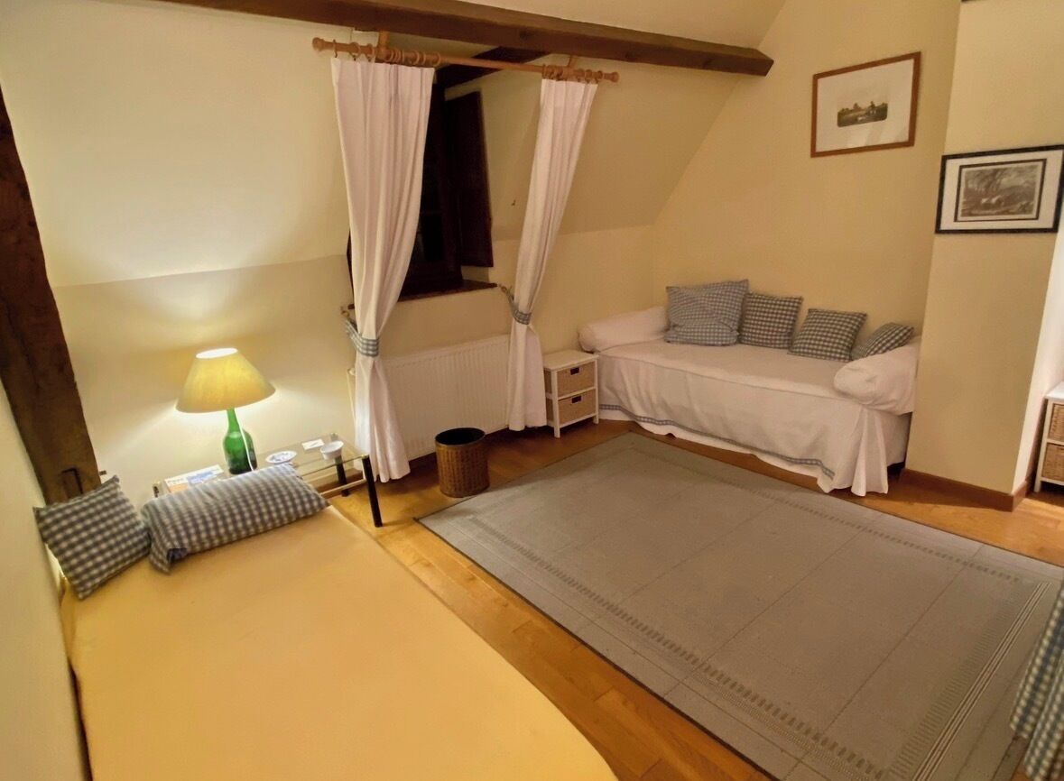Une chambre à coucher comprenant un lit, une table de chevet, une lampe, une fenêtre avec des rideaux, un canapé et un tapis.
