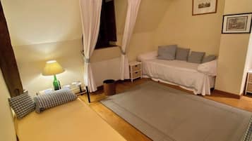 Une chambre à coucher comprenant un lit, une table de chevet, une lampe, une fenêtre avec des rideaux, un canapé et un tapis.