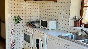 A kitchen with a stove, oven, microwave, and washing machine.