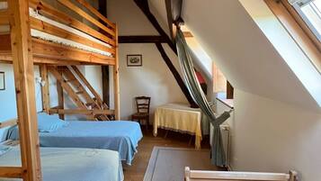 Une chambre de dortoir avec des lits superposés, une petite table et un hamac.