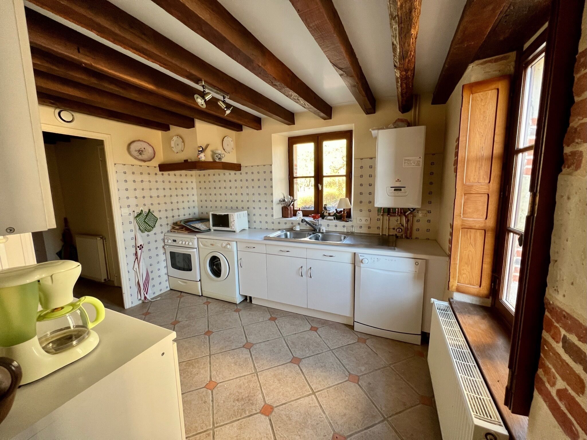 A kitchen with a washing machine, oven, microwave, and a water heater.