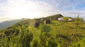 A rural landscape with traditional round-roofed buildings, a fenced area, and a hilly backdrop. - Eramon Paradise 360 (Nombre de Jesús)