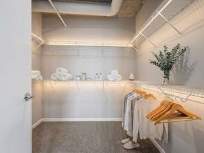 Ein Zimmer mit Kleiderstange, Spiegel und Pflanze.