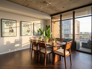 Ein Essbereich mit einem Holztisch und Stühlen, umgeben von großen Fenstern mit Blick auf die Stadt.