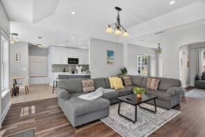 Una sala de estar moderna con un sofá modular, una mesa de centro y un comedor con una mesa pequeña y sillas.
