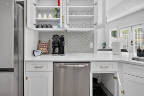 A modern kitchen with white cabinetry, a coffee maker, and a dishwasher. - 3BR Pool Home/Close to Beaches/Mayo/UNF/Towncenter (Jacksonville)