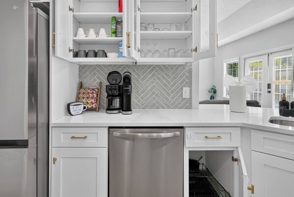 Una cocina moderna con armarios blancos, cafetera y lavavajillas.