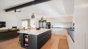 Una cocina moderna con una isla central, electrodomésticos integrados y un comedor con sofá y sillas.