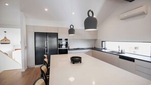 A modern kitchen with a central island, black appliances, and pendant lighting. - Noosa Sunsets - Luxury Home with Stunning Views (Noosa Heads)