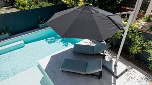 A swimming pool with a modern outdoor seating area, including a bench and a table. - Noosa Sunsets - Luxury Home with Stunning Views (Noosa Heads)