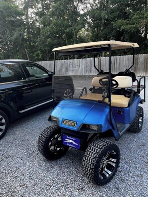 A blue golf cart parked on gravel with a black pickup truck beside it. - Free Golf Cart | 1 Mi to Downtown & Beach (Ocean Springs)