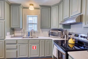 A kitchen with a sink, a microwave, a stove, and a yellow kettle. - Free Golf Cart | 1 Mi to Downtown & Beach (Ocean Springs)