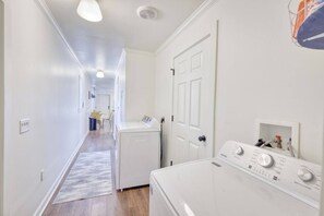 A laundry area with a washing machine and dryer, a door, and a hallway leading to a dining area. - Free Golf Cart | 1 Mi to Downtown & Beach (Ocean Springs)