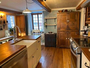 Une cuisine avec des meubles en bois, un évier, une cuisinière et un coin repas comprenant une chaise et une table.