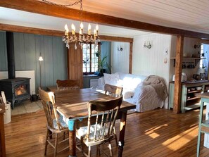 Ein gemütliches Zimmer mit Holztisch, Stühlen, einer Couch, einem Kamin und einer Küchenzeile.