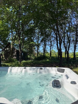 A hot tub surrounded by trees and a house in the background. - Île d'Orléans - The Fieldstone House (Saint-Jean-de-l'Île-d'Orléans)