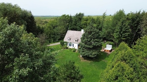 Ein Haus, umgeben von üppigem Grün, mit sichtbarer Whirlpoolanlage und blauem Himmel.