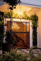 Imponente entrada con puerta de cristal, candelabro y escalera que conduce al interior.