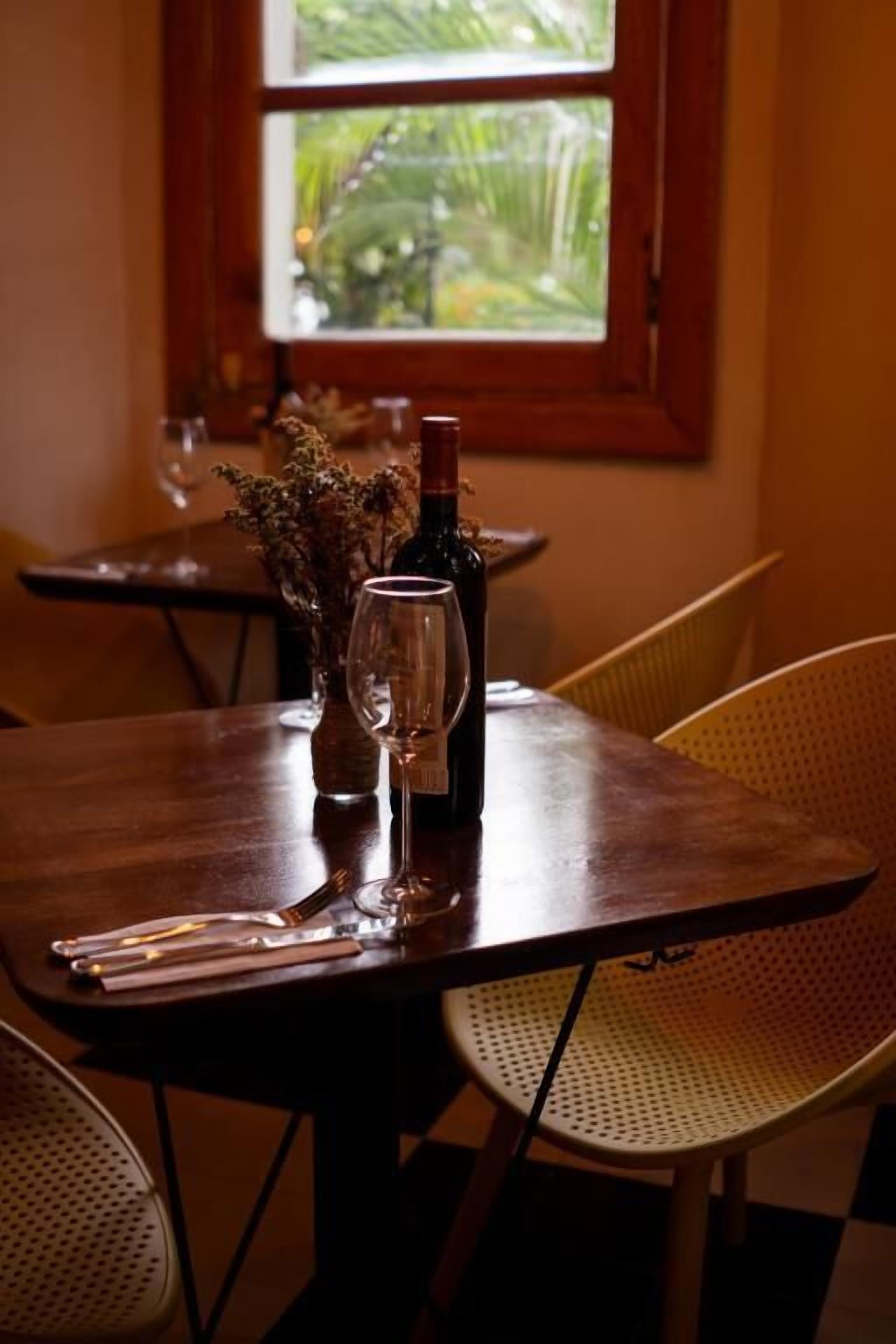 A dining table set with a wine bottle, glasses, and a menu.