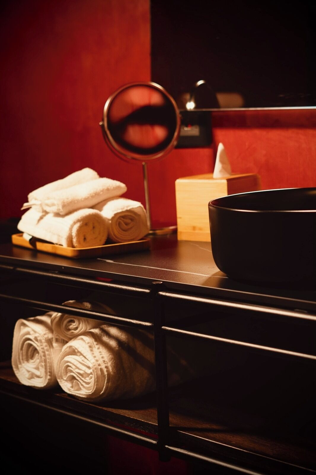 A bathroom with a mirror, towels, a soap dish, and a black basin.