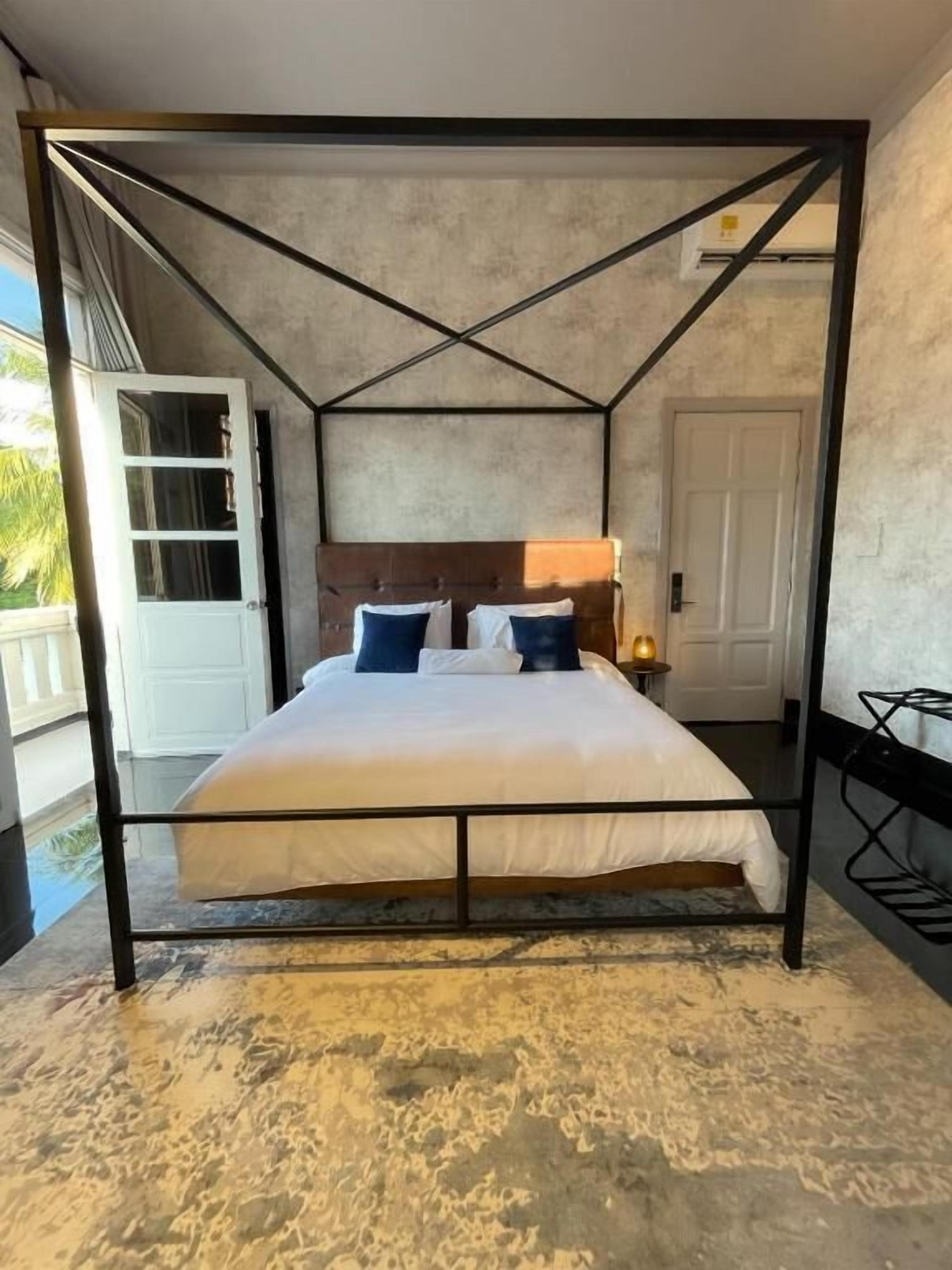 Un lit à baldaquin avec une tête de lit, du linge de lit blanc et un tapis à motifs.