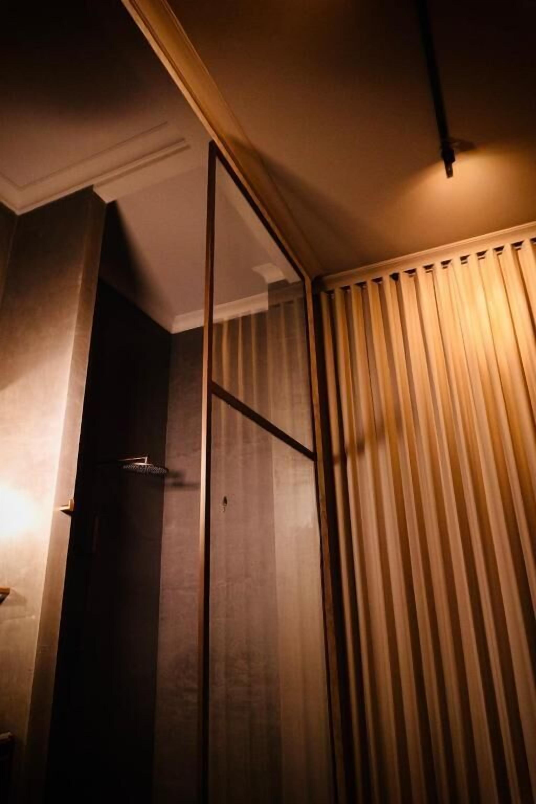 Una stanza con una porta in legno, un angolo doccia e una tenda.