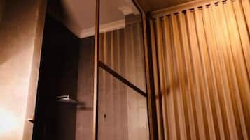Una stanza con una porta in legno, un angolo doccia e una tenda.