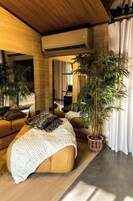 Una sala moderna con un sofá, una planta grande en maceta y un techo de madera.
