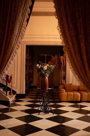 A lobby with a checkered floor, a vase with flowers, and a sofa.