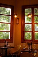 Comedor con ventanales de madera, una mesa con una botella y copas, y una lámpara colgante.