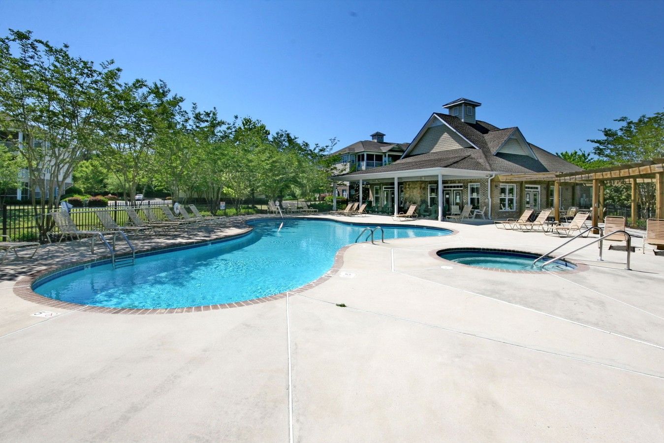 Une piscine avec des chaises longues, un patio couvert et une maison en arrière-plan.