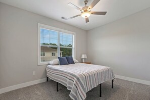A bedroom with a bed, a ceiling fan, a window, and a nightstand. - Brand NEW Calabash Condo (Calabash)