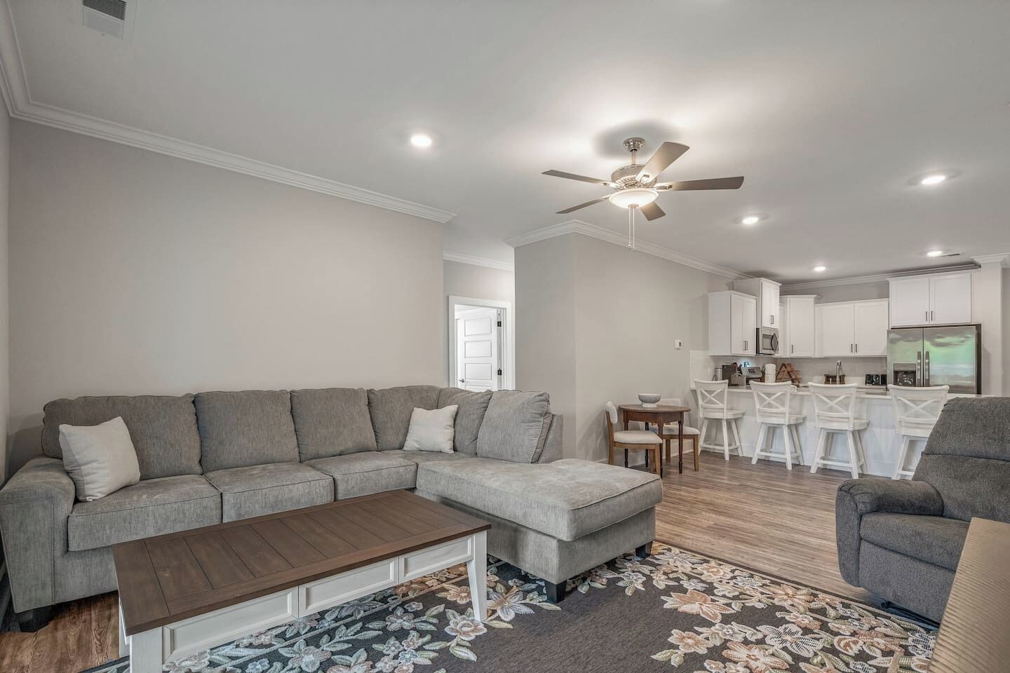 A modern living room with a sectional sofa, a coffee table, and a dining area with bar stools.