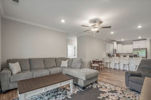 A modern living room with a sectional sofa, a coffee table, and a dining area with bar stools. - Brand NEW Calabash Condo (Calabash)